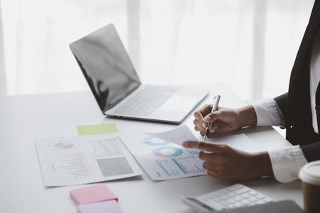 A female financier is reviewing company financial documents, monthly financial statement summary from the finance department. The concept of managing the company's finances for accuracy and growth.の写真素材