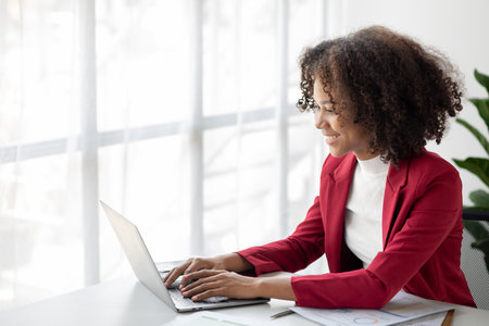A young American woman is a start-up businesswoman, she sits in the office, managing and running a business from a young generation. Startup business management concept.の写真素材