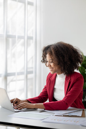 A young American woman is a start-up businesswoman, she sits in the office, managing and running a business from a young generation. Startup business management concept.の写真素材