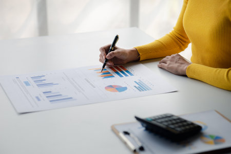 A female financier is reviewing company financial documents, monthly financial statement summary from the finance department. The concept of managing the company's finances for accuracy and growth.の写真素材