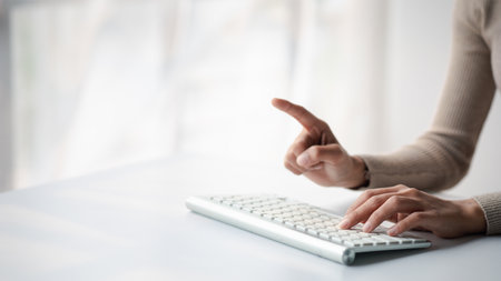 Person typing on a computer keyboard, businessman is working in a startup company's office, he is typing messages to his colleagues and making financial documents summarizing the meetings. Copy space.の写真素材
