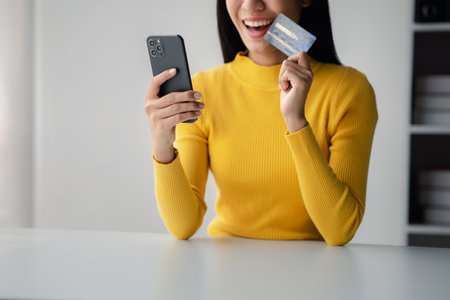 Beautiful woman holding a credit card, she uses a credit card to pay for goods and services online,...