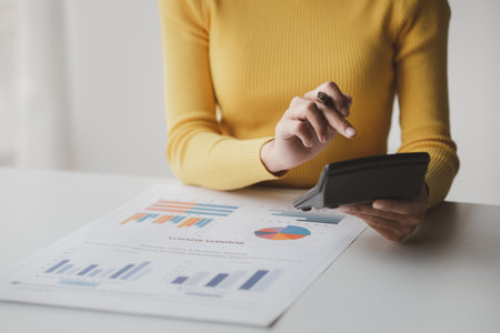 Businessman using a calculator to calculate numbers on a company's financial documents, she is analyzing historical financial data to plan how to grow the company. Financial concept.の写真素材