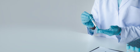 Lab assistant, a medical scientist, a chemistry researcher holds a glass tube through the blood sample, does a chemical experiment and examines a patient's blood sample. Medicine and research concept.の写真素材