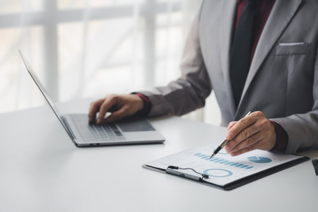 Businessman using a calculator to calculate numbers on a company's financial documents, she is analyzing historical financial data to plan how to grow the company. Financial concept.の写真素材