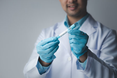Lab assistant, a medical scientist, a chemistry researcher holds a glass tube through the blood...