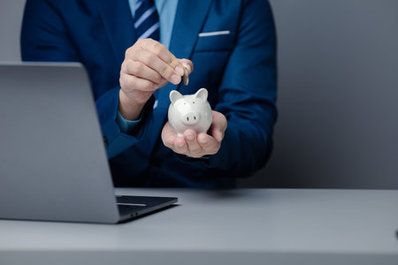 A person is holding a piggy bank, saving money and managing personal finances. Concept of increasing savings and savings by investing in stock mutual funds.の写真素材