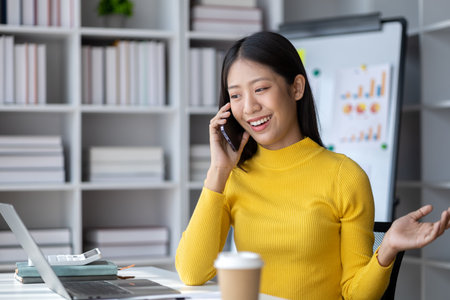 A young woman is a start-up businesswoman, she is talking on the phone, manages and runs her business from a young generation. Startup business management concept.の写真素材