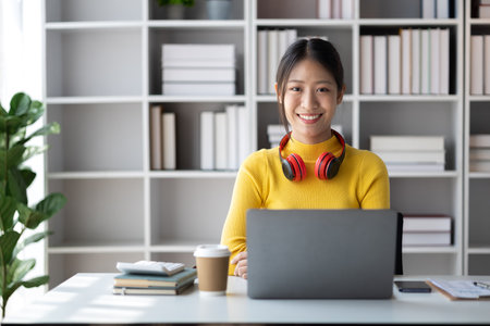 Teenage woman sitting in white room with laptop, she is a student studying online with laptop at...