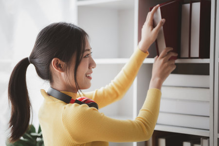 Woman in the library, she is reading and choosing books in the library, studying in the library. Education concept.の写真素材