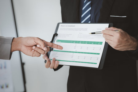Two businessmen pointed to the material for the meeting, working together to plan to develop and solve common business problems. Concept of business management for growth and quality.の写真素材