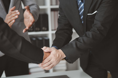 Business investor group holding hands, Two businessmen are agreeing on business together and shaking hands after a successful negotiation. Handshaking is a Western greeting or congratulation.の写真素材