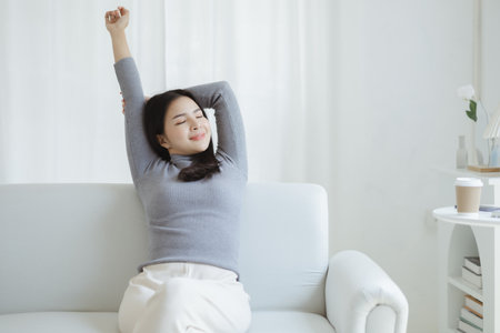 woman stretching relax. She is relaxing on the sofa in the living room on vacation. She does yoga poses to relax after a hard day's work. The idea of taking a break from hard work.の写真素材
