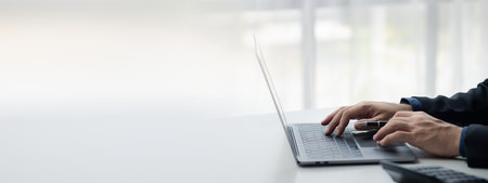 Person typing on laptop keyboard, businessman working on laptop, he is typing messages to colleagues...