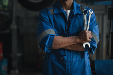 Car mechanic in uniform holding wrench at auto workshop, all kinds of auto specialists, expert auto repair and accredited auto repair centers.の写真素材