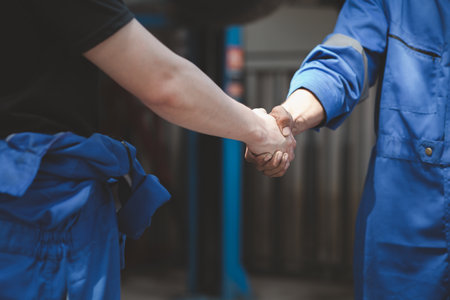 Two professional auto mechanics shaking hands, all kinds of car specialists, expert auto repair and standard auto repair center.の写真素材
