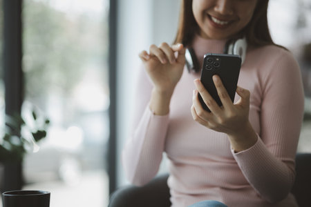 Woman playing with mobile phone, she is surfing the internet on her smartphone and socializing with her friends. and acquaintances on online platforms. Concept of social applications on mobile phones.の写真素材