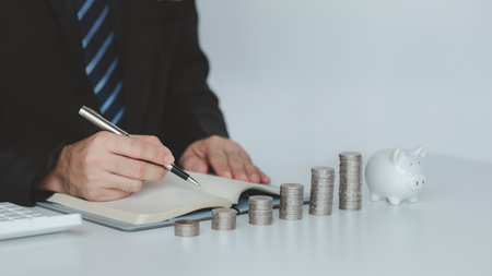 Person with pile of coins and piggy bank, money saving concept for future use and financial stability, salary management, personal finance, investment savings.の写真素材