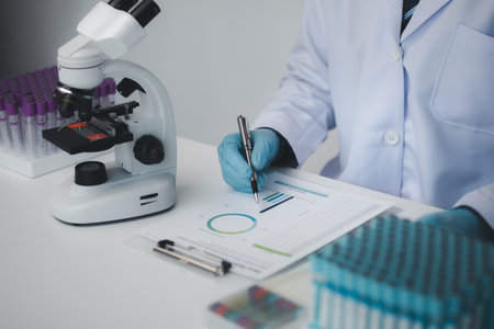 Lab assistant, medical scientist, chemistry researcher holds a glass tube through a chemical test tube, does a chemical experiment and examines a patient's sample. Medicine and research concept.の写真素材