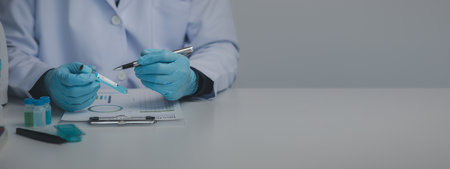 Lab assistant, medical scientist, chemistry researcher holds a glass tube through a chemical test tube, does a chemical experiment and examines a patient's sample. Medicine and research concept.の写真素材