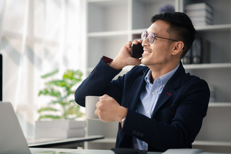 Man working in office and talking on the phone, he is young businessman, modern business management, start-up company run by young people, modern entrepreneur with new ideas. to be a business leader.の写真素材