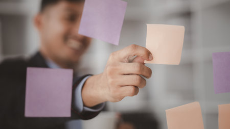 Businessman looking at  notes on mirror, he looks at data after a meeting between executives and department employees to discuss and grow the company. Management concept of a startup company.の写真素材
