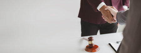 Lawyer and client shake hands, after winning a lawsuit where a lawyer hired by a client in a fraud case and proceeding in a fair and correct manner, the client wins the case. Fraud litigation concept.の写真素材