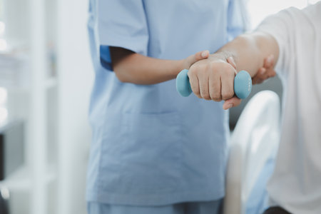 A physiotherapist doing physiotherapy for a patient in a hospital room, physiotherapy helps to recover from illness by moving the body and muscles. The concept of treating illnesses with physical therapy.の写真素材