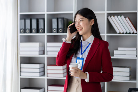 Asian woman talking on the phone, she is a salesperson in a startup company, she is calling customers to sell products and promotions. Concept of selling products through telephone channels.の写真素材