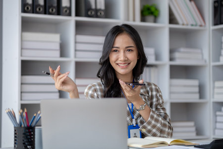 Beautiful asian woman looking at data on phone, businesswoman working in office attentively to grow and modernize start-up business, she is analyzing company's market and financial data.の写真素材