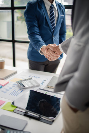 Two business men shake hands, Two businessmen are agreeing on business together and shaking hands after a successful negotiation. Handshaking is a Western greeting or congratulation.の写真素材