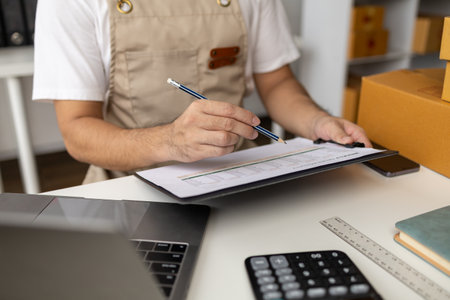 Man working, online shop owner checking orders from websites on the internet to confirm orders with customers who have ordered them and packing them for delivery. Concept of selling products online.の写真素材