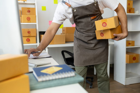 Male online shop owner, he checks orders on computer, online shop owner distributes products on...