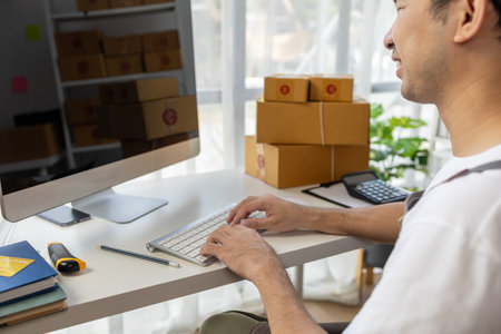 Male online shop owner, he checks orders on computer, online shop owner distributes products on...
