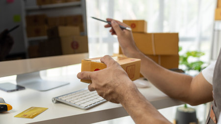 Male online shop owner, he checks orders on computer, online shop owner distributes products on website, packs orders and delivers them by private courier. Online shopping concept. eCommerce.の写真素材