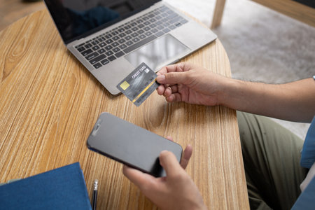 Asian man holding a credit card, he is filling in credit to pay for goods and services on the...