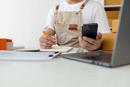 Person looking at customer information on a mobile phone, selling products online, packing orders from customers who place orders through online shopping sites. Selling products online and e-commerce.の写真素材