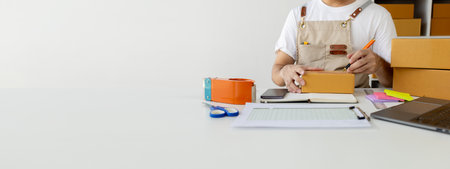 Person writing a customer's address on a parcel box, selling products online, packing orders from...
