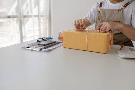 Owner of an online store on the website, online shop owner distributes products on website, packs products according to orders and delivers by private shipping company. Online shopping concept.の写真素材