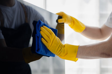 Person cleaning room, cleaning worker is using cloth to wipe computer screen in company office room. Cleaning staff. Concept of cleanliness in the organization.の写真素材