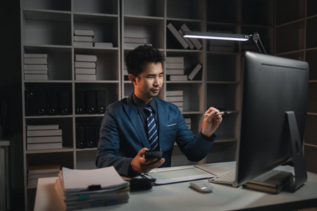 The male employee is in the office in the middle of the night, he is working hard and overtime. Overtime concept. Employees of private companies.の写真素材
