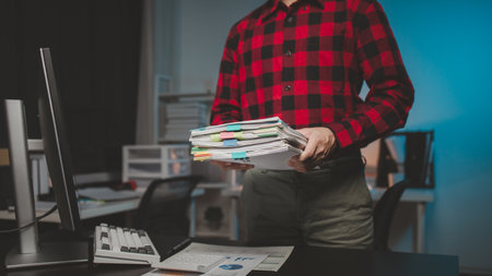 Office worker with stacks of documents, he is a startup company employee working in the office,...