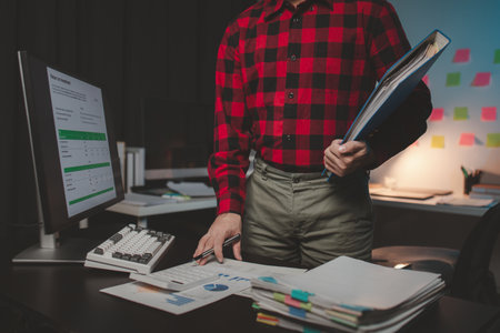 Office worker with stacks of documents, he is a startup company employee working in the office, working overtime, organizing office documents. Concept of working on important documents.の写真素材