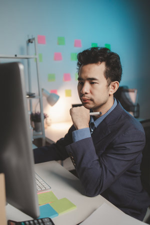 Asian male businessman working in the room. Startup company employees are working in the office at night, overtime, busy work, hard work. Overtime concept.の写真素材