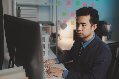 Asian male businessman working in the room. Startup company employees are working in the office at night, overtime, busy work, hard work. Overtime concept.の写真素材