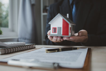 The real estate agent holds a sample house model presented to the client, the realtor explains the details of the house and the contract terms of the sale. The concept of selling housing estates.の写真素材