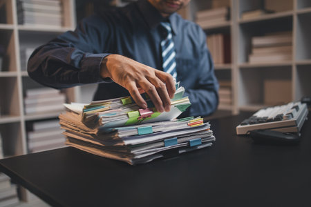 Startup company employees are rummaging through piles of paperwork for performance summaries, employees working overtime and working hard. Document management concept.の写真素材
