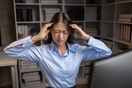 Company employees working overtime after work, working overtime after working hours due to heavy workload, employees are stressed and tired from working hard all day and continuously working overtime.の写真素材