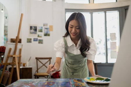 Asian woman is painting art. She is a professional artist. Watercolor artist is painting art on...