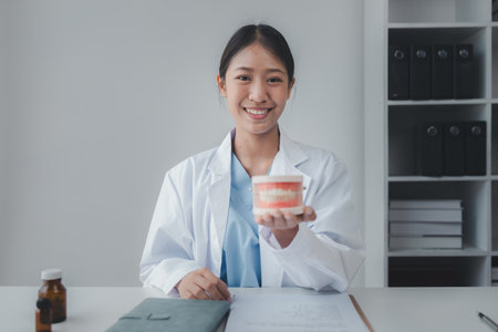 Female dentist with dentures for explaining teeth, recommending orthodontic guidelines, dentist...